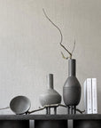 A 101Cph Duck Fat Dark Grey 111281 table adorned with vases and books, embracing the Cobra Arts Movement aesthetic. (Brand Name: 101 Copenhagen)