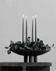 A minimalist black 101Cph Duck Plate Big Coffee 214049 candle holder featuring delicate eucalyptus leaves on top, perfect for a Scandinavian home.