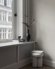 A 101Cph Duck Slim Coffee 111280 ceramic stool placed in front of a window in Copenhagen.