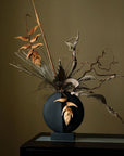 A whimsical 101Cph Guggenheim Mini Black 111126 vase with a bunch of leaves in it, perfect for adding a quirky touch to any interior setting. (brand: 101 Copenhagen)