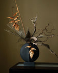 A whimsical 101Cph Guggenheim Mini Black 111126 vase with a bunch of leaves in it, perfect for adding a quirky touch to any interior setting. (brand: 101 Copenhagen)