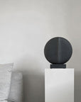 In an interior setting, a whimsical 101Cph Guggenheim Mini Black 111126 from 101 Copenhagen sits atop a white pedestal, resembling quirky vases.