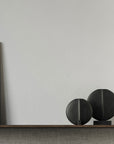 A wooden shelf with two 101Cph Guggenheim Mini Black 111126 vases and a whimsical painting on it, creating an intriguing interior setting.