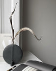 A quirky 101Cph Guggenheim Petit Black 213042 vase sits on a desk next to a notebook.