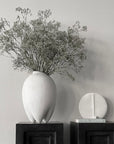 A 101Cph Guggenheim Petit Bone White 213043 vase sits on top of a black shelf, adding a touch of quirkiness to the overall decor. (Brand: 101 Copenhagen)