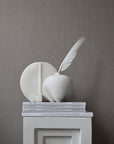 A white 101Cph Guggenheim Petit Bone White 213043 sculpture, inspired by the Cobra Arts Movement, sits on top of a bookcase in Copenhagen.