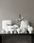 A quirky 101Cph Guggenheim Petit Bone White 213043 vase sits on top of a black shelf. (Brand Name: 101 Copenhagen)
