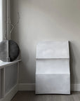 Modern interior with a grey ceramic vase from 101 Copenhagen and a concrete wall art piece.