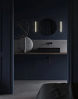 Modern bathroom with dark blue walls, round mirror, and sculptural vase from 101 Copenhagen