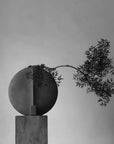 A sculptural vase with a branch against a gray background from 101 Copenhagen at Spacio retail stores in Mumbai & Kolkata.