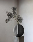 Decorative vase with a branch on a neutral background from 101 Copenhagen at Spacio retail stores in Mumbai & Kolkata.