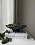 A 101Cph Medusa Tray Mini Coffee 221064 ceramic bowl sits on top of books and moss.