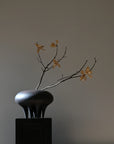 A 101Cph Medusa Vase Big Coffee 221061 by 101 Copenhagen with a branch on top of it.