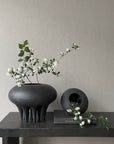 A 101Cph Medusa Vase Big Coffee 221061 by 101 Copenhagen with white flowers on a table.