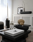 Modern interior with black table, decorative items, and a white wall.