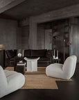 Modern living room with dark walls, a brown sofa, and light gray chairs.