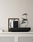 Decorative setup with 101 Copenhagen Shinju platter& black and white framed art on a shelf against a light wall.