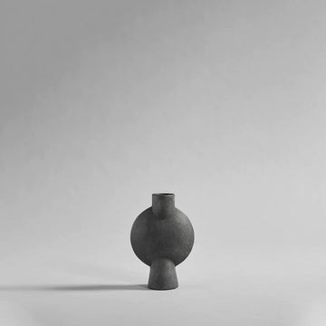 A 101Cph Sphere Bubl Mini Dark Grey 111029 finished vase, part of the Scandinavian brand 101 Copenhagen, sitting on a grey background.