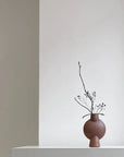 A 101Cph Sphere Bubl Mini Terracotta 203010 vase sits on a table in a white room. (Brand: 101 Copenhagen)