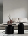 A living room with two black vases, one of which is the 101Cph Sphere Bubl Mini Terracotta 203010 vase by 101 Copenhagen, and a coffee table.