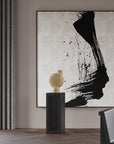 An abstract painting in black and white hangs above a wooden table in a living room, enhanced by the 101Cph Sphere Vase Bubl Big Sand 201014 from 101 Copenhagen.