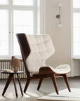Modern chair with white cushion in a bright room with large windows and a 101 Copenhagen sculptural vase.