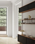 Modern interior with a shelf, lamp, and books in a room with large windows.