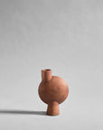 Terracotta colour sculptural vase vase on a light gray background from 101 Copenhagen at Spacio retail stores in Mumbai & Kolkata.