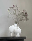 Two white 101 Copenhagen Sphere Vases from the popular Scandinavian brand, Mini Bubble White, sitting elegantly on a black table.
