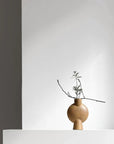 A 101Cph Sphere Vase Bubl Mini Ocher 111180 by 101 Copenhagen sits on top of a white wall.