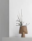 A 101Cph Sphere Vase Square Mini Ocher 111181 by 101 Copenhagen with an ochre finish sitting on top of a white wall.