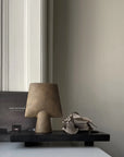 A 101Cph Sphere Vase Square Mini Ocher 111181 lamp by 101 Copenhagen sits on a table next to a book.