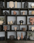 A shelf full of various vases and pots, including a 101 Copenhagen Sphere Vase Square Mini Ocher 111181 with an ochre finish.