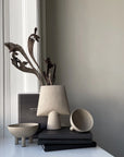 Decorative items including a vase, books, and a cup on a surface with a neutral background.