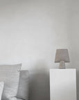 Gray ceramic vase on a white pedestal against a plain wall with gray cushions from 101 Copenhagen at Spacio retail stores in Mumbai & Kolkata.
