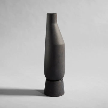 A black 101Cph Sphere Vase Tall Coffee 111205 on a grey background by the Scandinavian brand, 101 Copenhagen.