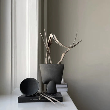 A dark grey vase on a console with coffee table books and table decor from 101 Copenhaged. Styled by Spacio Interior Styling team