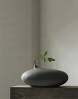 Dark gray vase with a small plant on a neutral background from 101 Copenhagen at Spacio retail stores in Mumbai & Kolkata.
