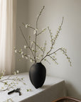Black vase with white flowers on a tablecloth from 101 Copenhagen at Spacio retail stores in Mumbai & Kolkata.