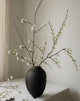 Black vase with white flowers on a tablecloth from 101 Copenhagen at Spacio retail stores in Mumbai & Kolkata.