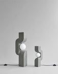 Two concrete table lamps with spherical lights on a gray background from 101 Copenhagen at Spacio retail stores in Mumbai & Kolkata.