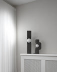 Two black abstract sculptures on a white surface against a gray wall from 101 Copenhagen at Spacio retail stores in Mumbai & Kolkata.