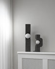 Two black abstract sculptures on a white surface against a gray wall from 101 Copenhagen at Spacio retail stores in Mumbai & Kolkata.