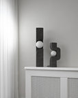 Two black abstract sculptures on a white surface against a gray wall from 101 Copenhagen at Spacio retail stores in Mumbai & Kolkata.