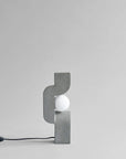 Modern wall lamp with concrete-like finish on a light gray background from 101 Copenhagen at Spacio retail stores in Mumbai & Kolkata.