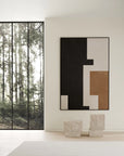 Modern interior with abstract art on a white wall, large window showing trees, and two limestone plinths.
