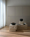 Modern interior with limestone plinth and decorative items against a plain wall.