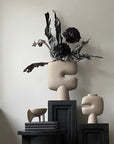 Decorative sculptural vase with dried plants on podiums (plinths/ pedestals) against a neutral wall from 101 Copenhagen at Spacio retail stores in Mumbai & Kolkata.