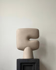 Beige abstract sculptural vase on a black base against a plain background from 101 Copenhagen at Spacio retail stores in Mumbai & Kolkata.