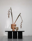 A pair of hollow sculptures on a black platform with dried plants against a white background from 101 Copenhagen at Spacio retail stores in Mumbai & Kolkata.